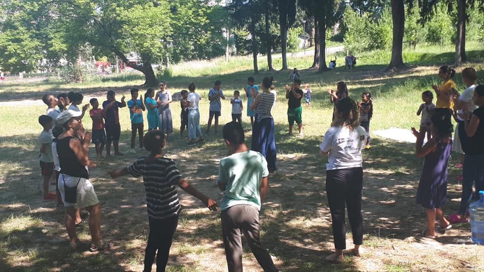 Children and adults playing a group game outdoors in a park