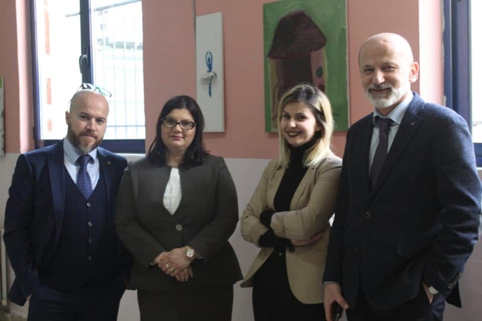 Four adults standing together in front of children's artwork