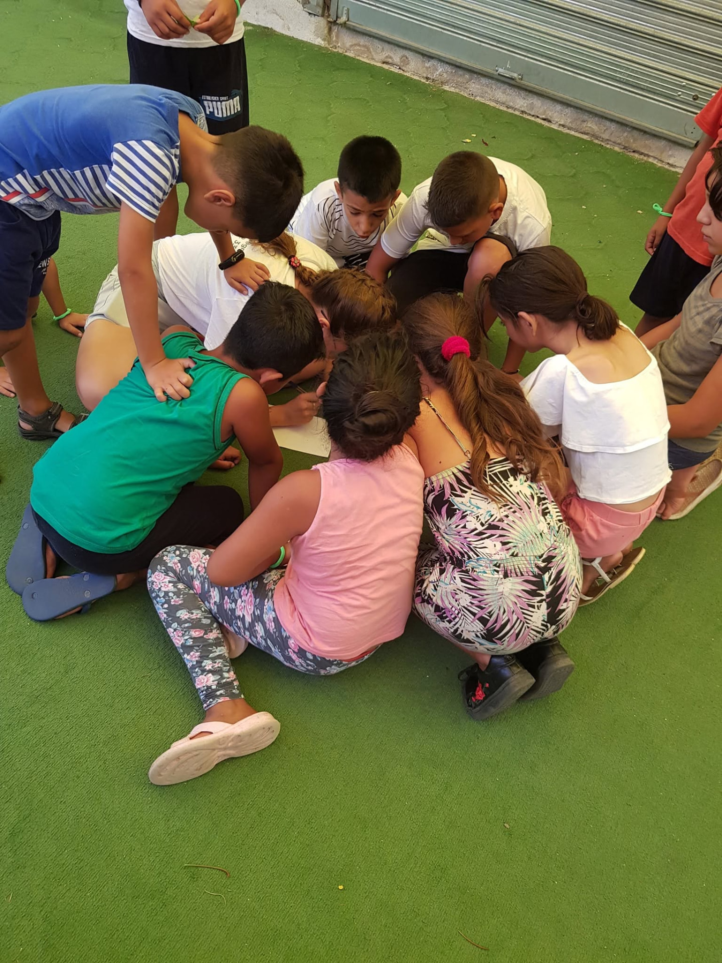 A group of children huddled together over a sheet of paper