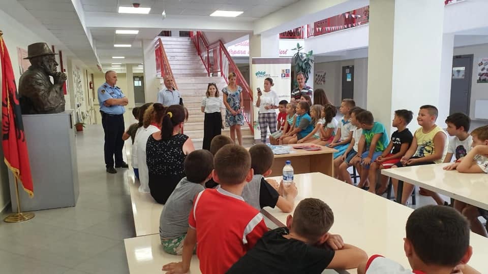 Children seated at tables listening to a talk in a school hall